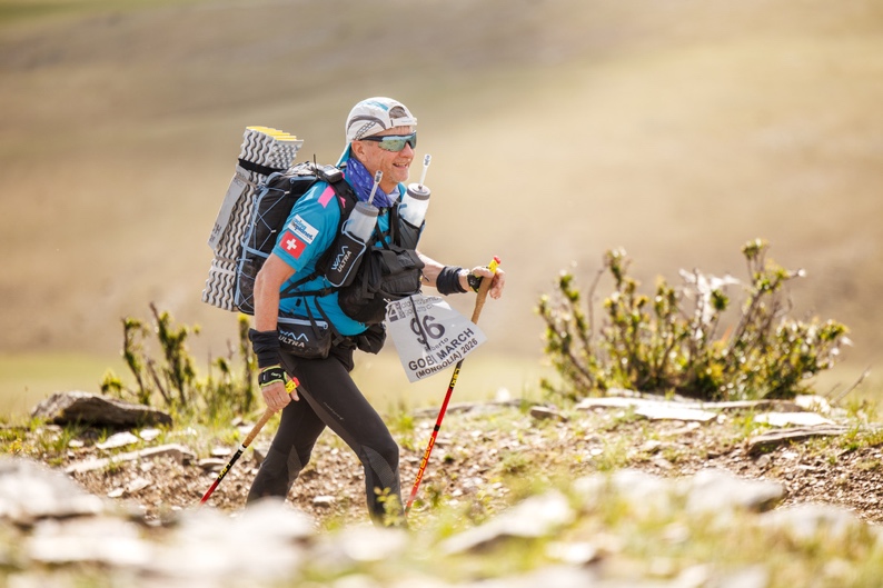 Roberto Rivola hiking with poles and a fully loaded backpack, sleeping mat strapped on top, during the Gobi March in Mongolia